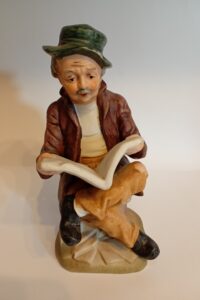 Old man reading book figurine